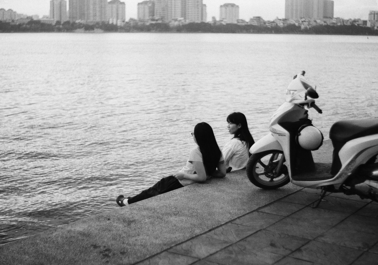 A woman laying on the ground next to a scooter
